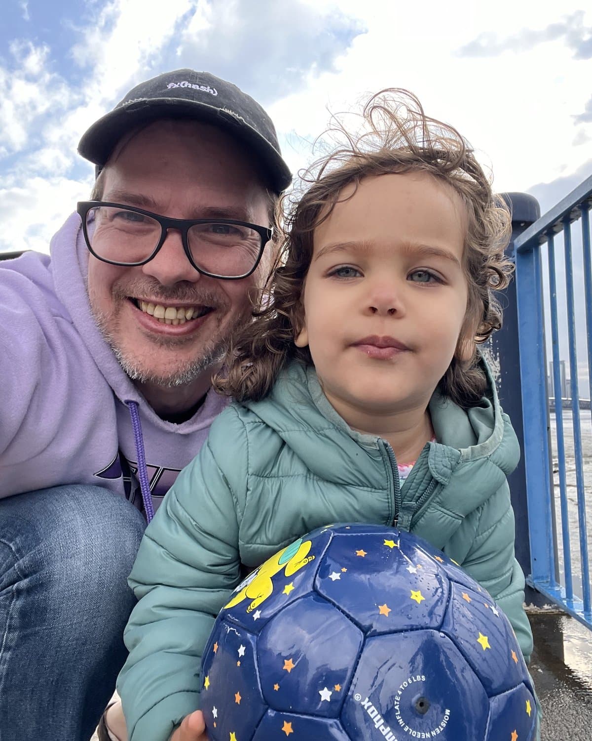 Noah Watkins with his daughter and a ball by the river